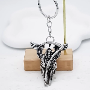 Silver skull angel keychain in vintage alloy finish hanging on a minimal display stand