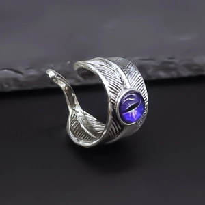 Macro detail of silver feather ring featuring a mystical purple cat eye gemstone setting
