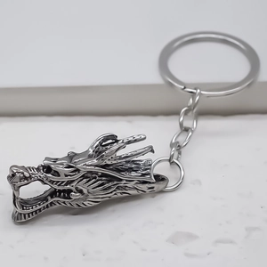 Porte-clés dragon en argent vintage avec détails fins sur marbre blanc