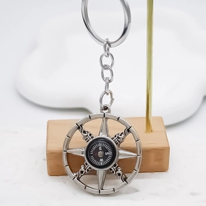 Detailed close-up of a silver nautical compass keychain with a ship wheel frame design