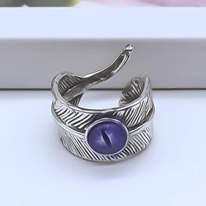 Macro shot of silver feather ring featuring a central purple gemstone with evil eye effect