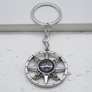 Vintage silver metal compass keychain with geometric compass rose pendant on stone background