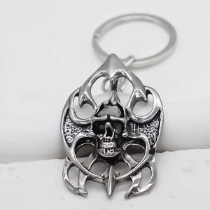 Close-up of silver metal skull keychain with flame pattern frame and ring attachment