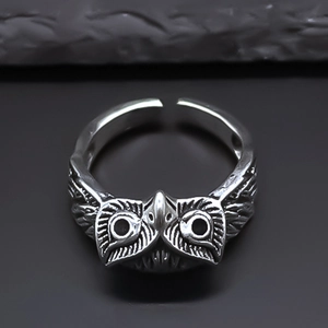 Macro detail of retro silver owl ring showing intricate feather texture and owl eyes
