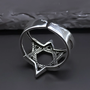 Detailed view of silver hexagram star ring with hammer texture finish on rock background