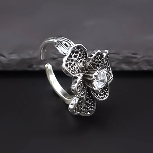 Vintage floral ring with central zircon and adjustable band on a dark stone background