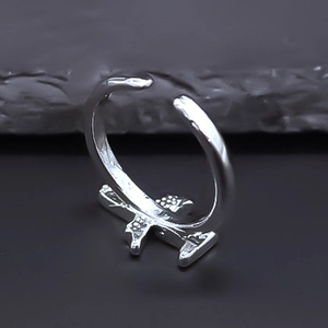 Detail shot of a silver airplane-shaped open ring on a dark stone texture background