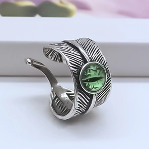 Macro detail of antique silver feather ring featuring a green angel eye gemstone center