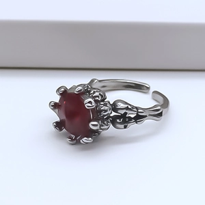 Detail of gothic silver ring featuring a red gemstone held by claws and skull accents