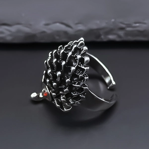 Gros plan sur une bague hérisson punk rétro avec yeux en pierre rouge et fini argent