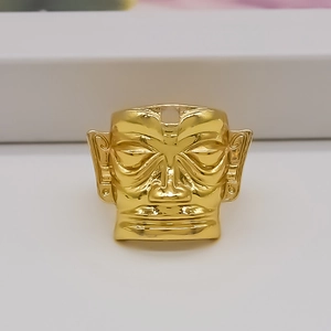Detailed relief of gold mask ring inspired by ancient symbols on white stand
