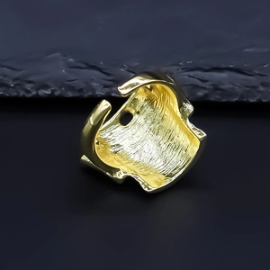 Macro view of golden mask ring showing thick irregular profile and brushed metal texture