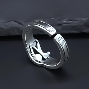 Macro shot of silver open ring featuring vintage hollow cat pattern on dark stone background