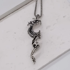 Detailed close-up of a silver dragon pendant with intricate 3D scales and punk style chain