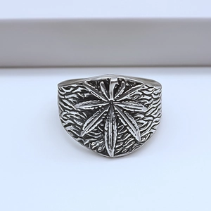 Detailed view of vintage silver maple leaf ring with rugged rock texture on white steps