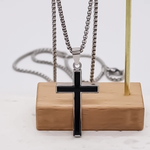 Collier minimaliste avec pendentif croix noire et chaîne en acier inoxydable sur bois