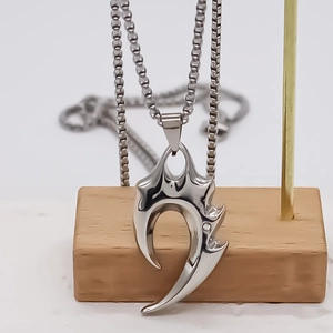 Dettaglio della collana a catena argento con pendente a cono geometrico su base legno