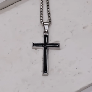 Vue rapprochée du pendentif croix en acier poli avec émail noir sur chaîne vénitienne