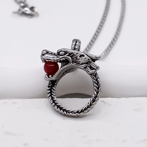 Collier dragon vintage en argent avec perle rouge et écailles détaillées sur fond blanc