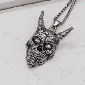 Detail shot of vintage silver devil skull pendant with cross symbol on stone surface