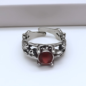 Détail macro d'une bague gothique tête de mort avec pierre rouge et finition argent antique