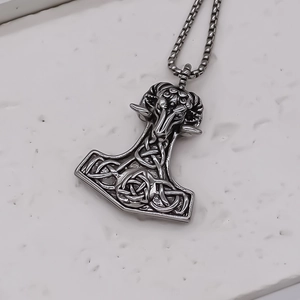 Macro detail of retro stainless steel Mjolnir pendant with Celtic knots and ram head carving