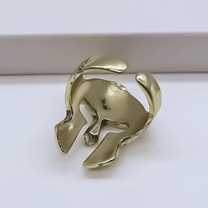Detail shot of a vintage golden Spartan helmet ring on a minimalist white platform