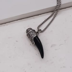 Macro detail of wolf tooth pendant with vintage silver runes and square bead chain