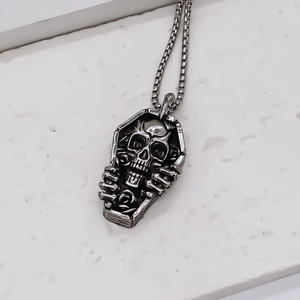 Macro detail of retro stainless steel coffin pendant with skull and rose motifs
