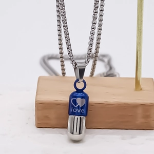 Détail du pendentif capsule bleu et argent avec gravure de cœur sur une chaîne