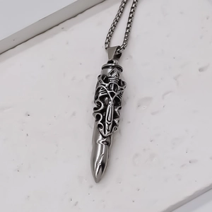 Macro shot of silver bullet pendant with gothic hollow carving and box chain details