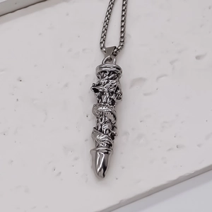 Détail du relief de dragon argenté sur pendentif cylindre avec chaîne à mailles