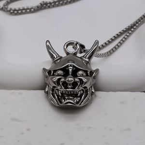 Macro shot of retro silver devil mask pendant with detailed demonic carving and pearl chain