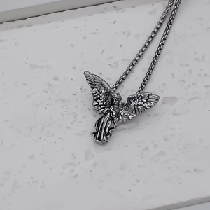 Macro shot of silver angel pendant with intricate wings and antique box chain texture