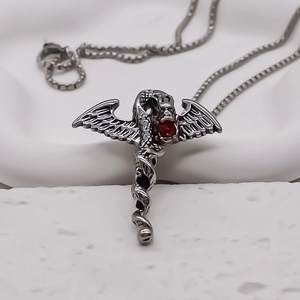 Detailed close-up of a vintage dragon sword pendant with a vibrant red center gemstone