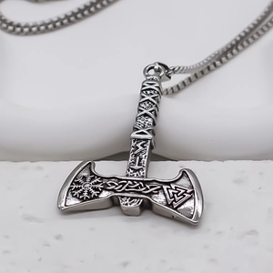 Macro detail of vintage Viking double axe pendant with Nordic runes and Valknut symbol