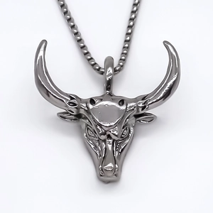 Collier avec pendentif tête de taureau en métal gris foncé avec détails gravés sur fond blanc