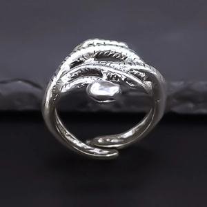 Adjustable silver octopus ring with organic feather texture on dark stone surface