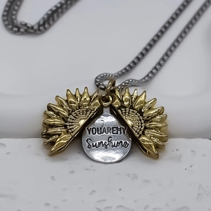 Détail d'un collier médaillon tournesol ouvrant avec gravure You Are My Sunshine