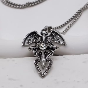 Macro shot of gothic silver cross pendant with bat wings and sparkling center stone