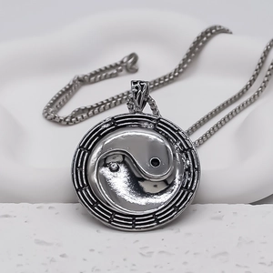 Gros plan du pendentif Yin Yang vintage argenté avec symboles Bagua et chaîne