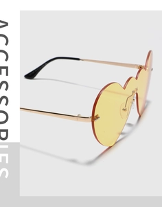 Détail de lunettes de soleil coeur jaunes avec monture fine en métal doré et style y2k