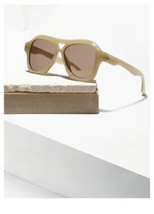 Detail of beige double-bridge square pilot sunglasses with dark brown lenses on stone
