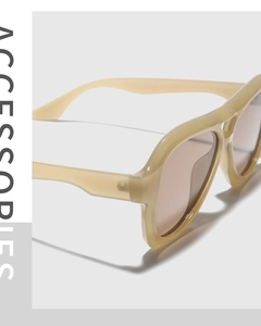Close-up of thick beige frame sunglasses with amber lenses and refined hinge detail