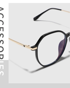 Detail of polygonal black glasses frame with gold metal legs and heart decoration