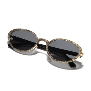 Ovale Retro-Sonnenbrille mit goldfarbenem Metallrahmen und funkelndem Kristallbesatz