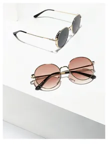 Detail of vintage round metal sunglasses featuring hollowed-out side frames and gold finish