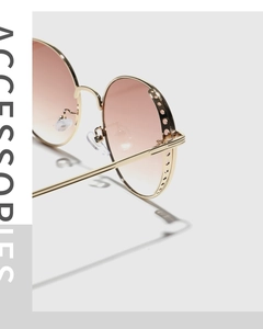 Detailed side view of round sunglasses with golden hollow frames and gradient brown lenses