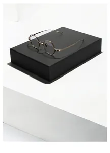 Detailed view of round metal eyeglasses with thin gold temples on a black display stand