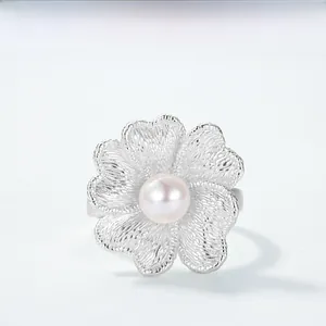 Macro detail of orchid flower ring with brushed silver petals and a pink pearl inlay
